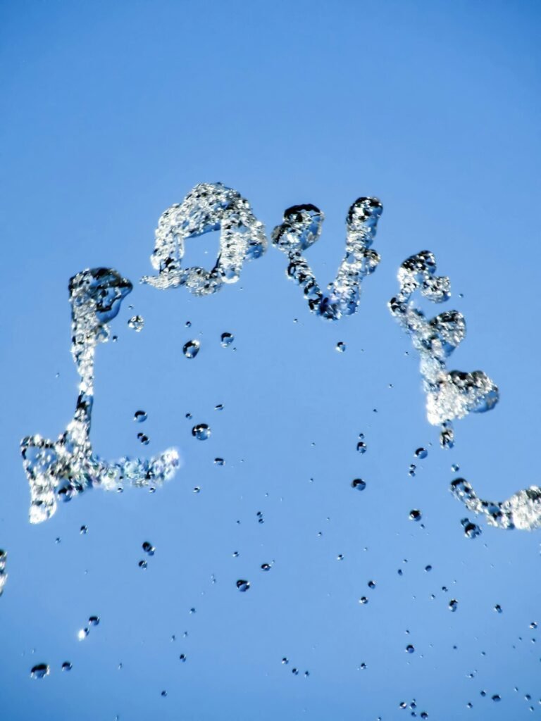 Capture of a streaming water fountain cascading down spelling out the word LOVE against the blue sky